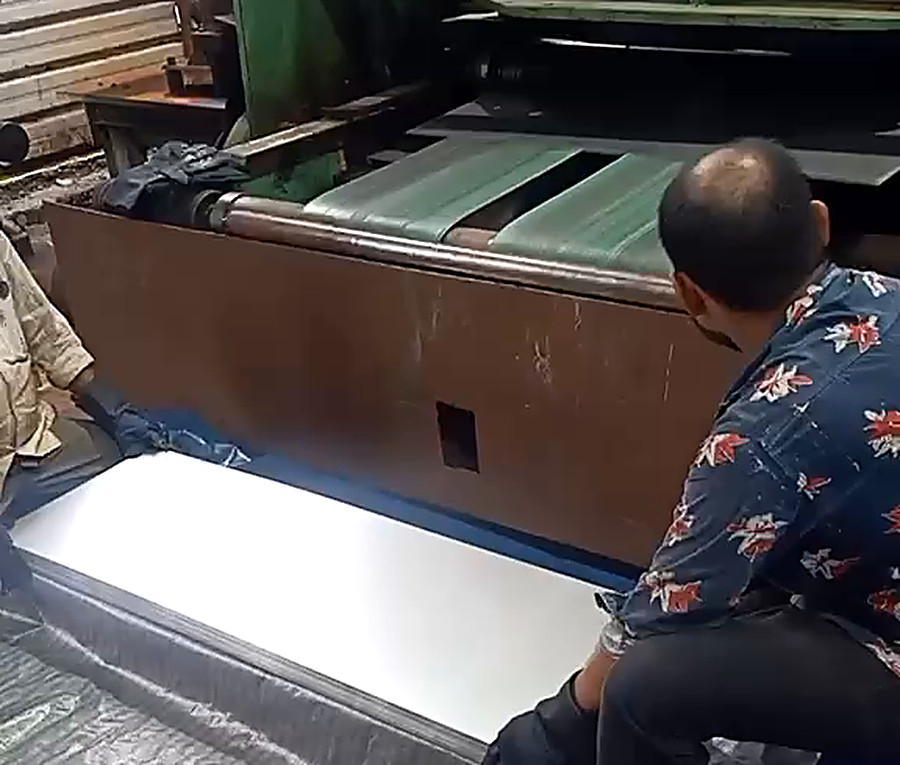Operator stacking a sheared stainless steel sheet on dunnage